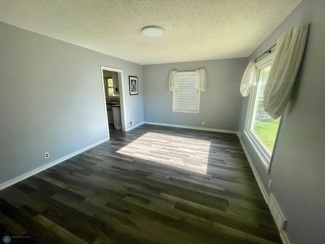 1630 7th St N, Fargo, ND 58102 - empty room featuring a textured ceiling, plenty of natural light, dark wood-style flooring, and baseboards