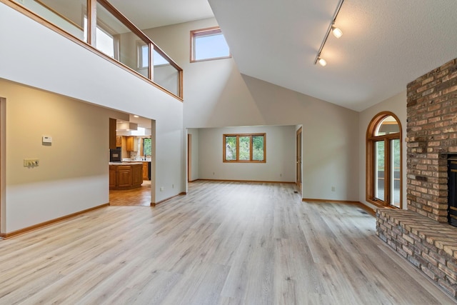 4306 Woods Way, Minnetonka, MN 55345 - unfurnished living room featuring a brick fireplace, track lighting, light wood-style floors, high vaulted ceiling, and baseboards