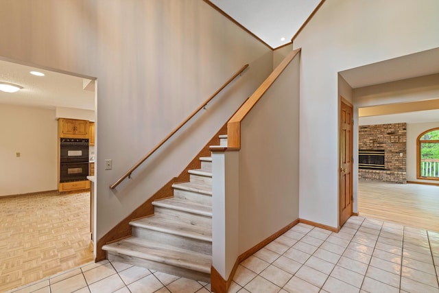 4306 Woods Way, Minnetonka, MN 55345 - stairway with baseboards, a high ceiling, tile patterned floors, and a fireplace