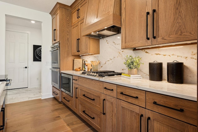 15630 112th St, Dayton, MN 55369 - kitchen with appliances with stainless steel finishes, custom range hood, brown cabinets, tasteful backsplash, and light stone counters
