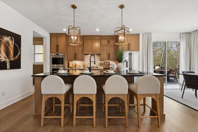 15630 112th St, Dayton, MN 55369 - kitchen with a kitchen island with sink, baseboards, high quality fridge, a kitchen bar, and wood finished floors