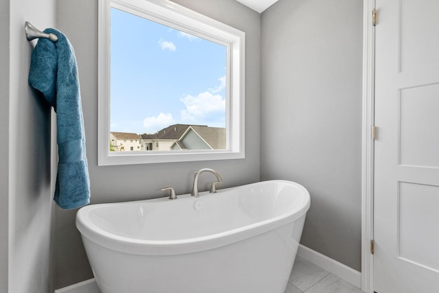 736 Blackbird Cir, Delano, MN 55328 - bathroom featuring marble finish flooring, a freestanding tub, baseboards, and healthy amount of natural light