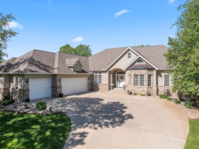 2508 4th Ave NW, Austin, MN 55912 - view of front of house with an attached garage, concrete driveway, a shingled roof, and stone siding