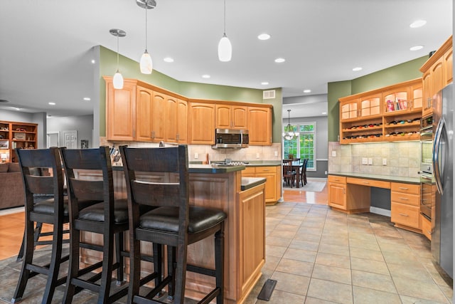 2508 4th Ave NW, Austin, MN 55912 - kitchen with stainless steel microwave, a kitchen bar, backsplash, a peninsula, and light tile patterned floors