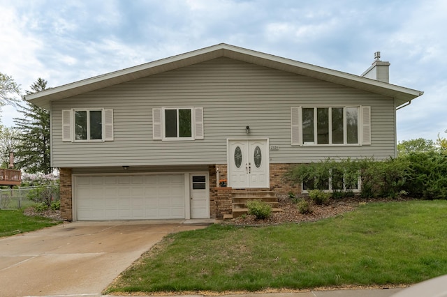 split foyer home with an attached garage, brick siding, a chimney, and driveway
