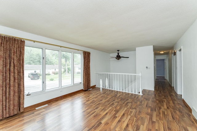 spare room with wood finished floors, a ceiling fan, and baseboards