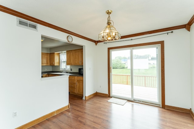 kitchen with ornamental molding, light wood-type flooring, a chandelier, baseboards, and dark countertops
