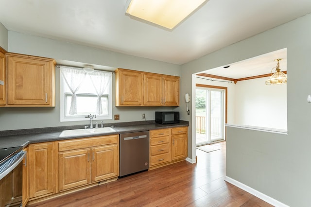 kitchen with a sink, stainless steel appliances, dark countertops, and plenty of natural light