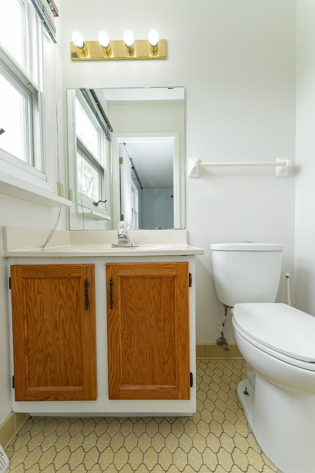 half bath with toilet, vanity, and baseboards