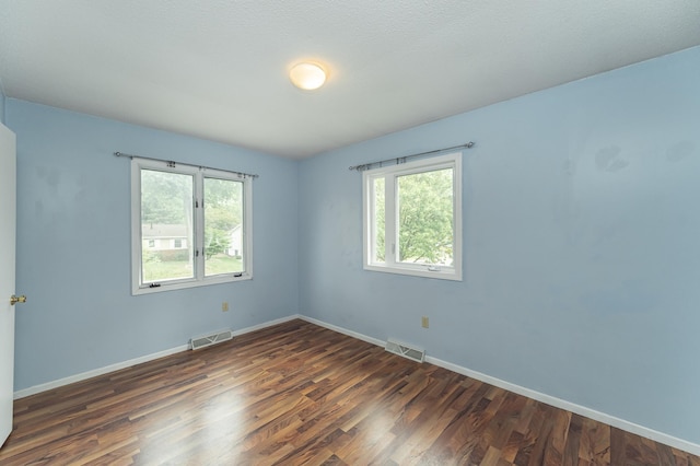 empty room with healthy amount of natural light, wood finished floors, and baseboards