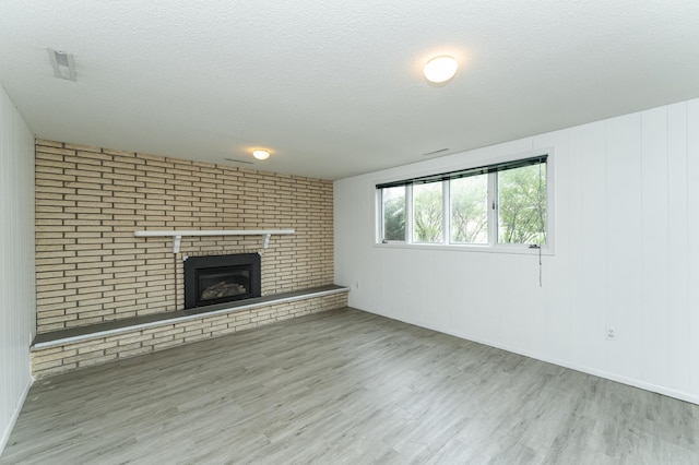 unfurnished living room featuring wood finished floors, a fireplace, and a textured ceiling