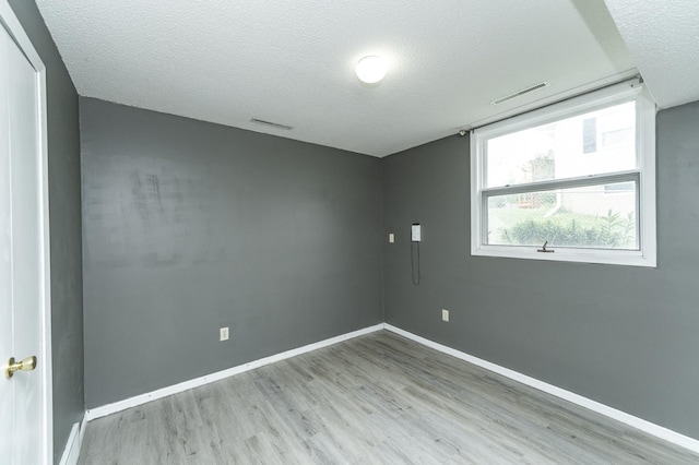 empty room featuring wood finished floors, a textured ceiling, and baseboards