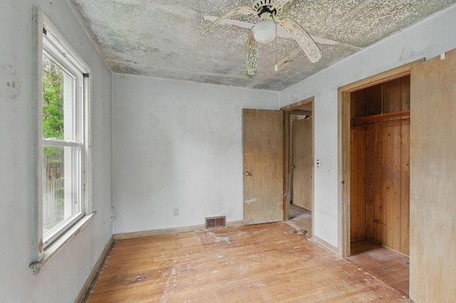 unfurnished bedroom featuring wood finished floors, multiple windows, a closet, and ceiling fan