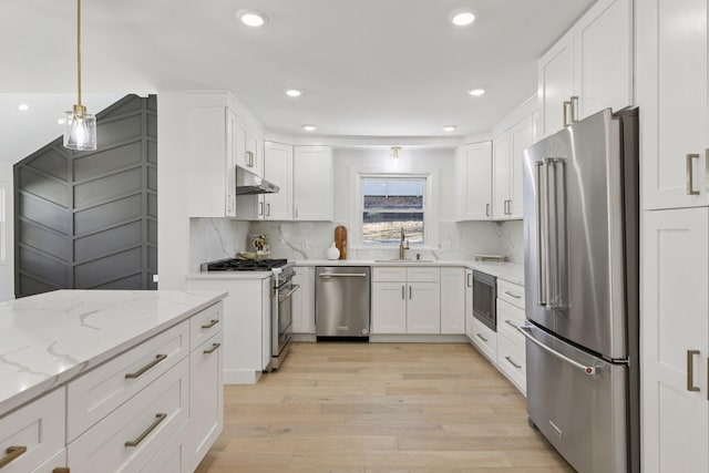 1022 Fairview Ave S, Saint Paul, MN 55116 - kitchen with premium appliances, under cabinet range hood, a sink, light wood finished floors, and white cabinets