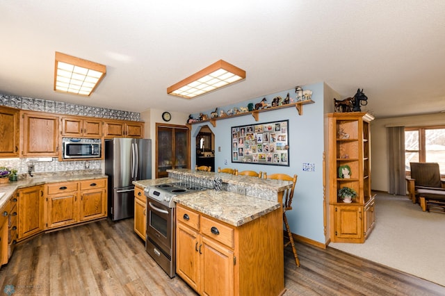 28040 Anchor Rd, Detroit Twp, MN 56501 - kitchen with stainless steel appliances, wood finished floors, a center island, a breakfast bar, and tasteful backsplash