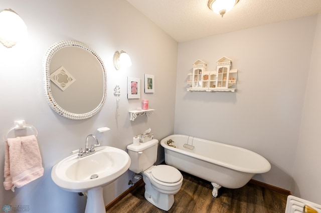 28040 Anchor Rd, Detroit Twp, MN 56501 - bathroom with wood finished floors, a freestanding tub, toilet, a sink, and a textured ceiling