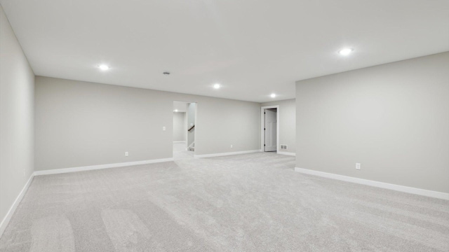 spare room featuring stairway, recessed lighting, light colored carpet, and baseboards