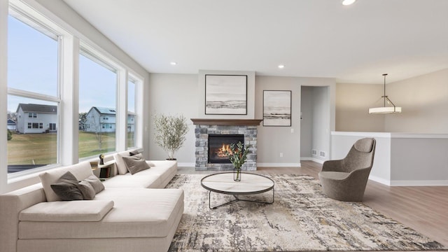 living room with wood finished floors, baseboards, recessed lighting, and a fireplace
