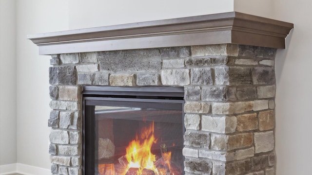 detailed view of a glass covered fireplace and baseboards