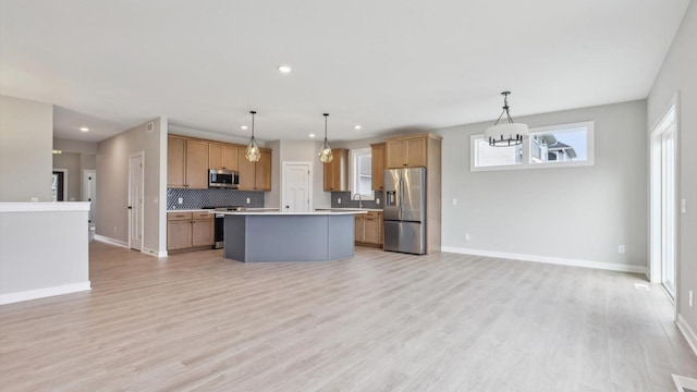 kitchen featuring stainless steel appliances, open floor plan, light countertops, a kitchen island, and backsplash