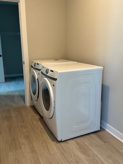 washroom featuring washer and dryer, light wood-style floors, and baseboards