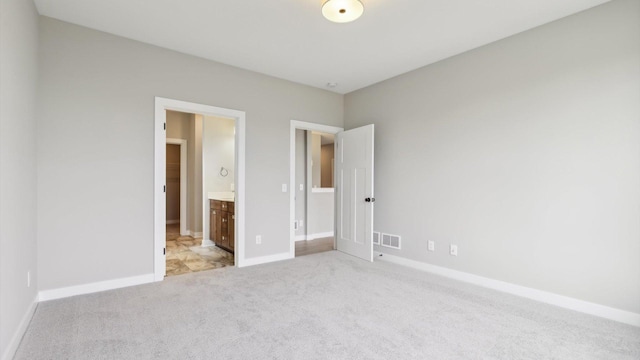 unfurnished bedroom featuring light carpet, baseboards, and connected bathroom