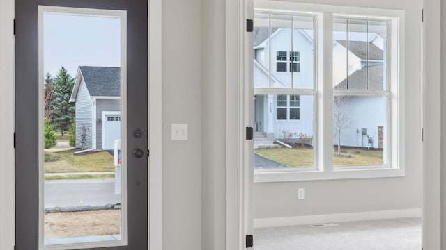entryway with baseboards, plenty of natural light, and carpet