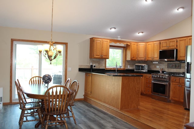1803 214th Ave NE, East Bethel, MN 55011 - kitchen with appliances with stainless steel finishes, a peninsula, tasteful backsplash, a chandelier, and wood finished floors