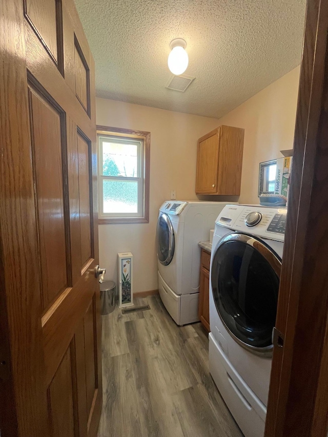 1803 214th Ave NE, East Bethel, MN 55011 - laundry room featuring washer and dryer, wood finished floors, a textured ceiling, and cabinet space