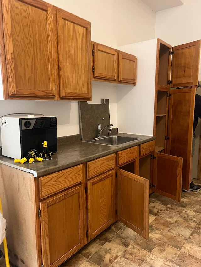 19997 Stockyard Rd, Bagley, MN 56621 - kitchen featuring a sink, dark countertops, brown cabinets, and stone finish flooring