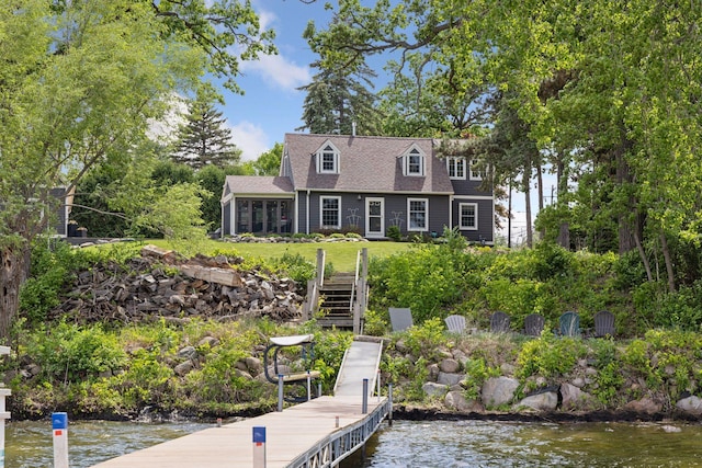 dock area with stairway, a water view, and a yard