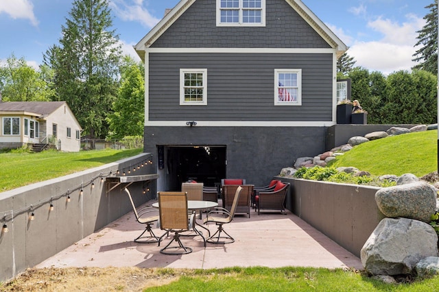 back of property featuring a patio, a garage, a lawn, and driveway