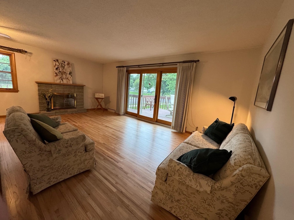 3401 Yukon Ave S, Saint Louis Park, MN 55426 - living area with wood finished floors, plenty of natural light, a stone fireplace, and a textured ceiling