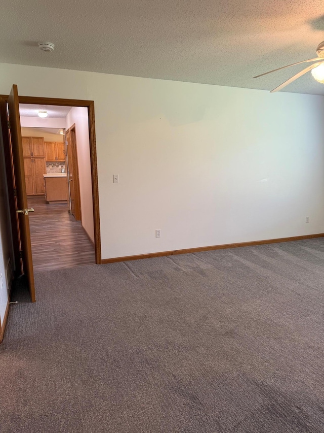 446 30th St N, Moorhead, MN 56560 - empty room with dark colored carpet, a textured ceiling, ceiling fan, baseboards, and a smoke detector