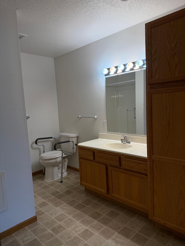 446 30th St N, Moorhead, MN 56560 - bathroom featuring toilet, vanity, a shower, a textured ceiling, and baseboards