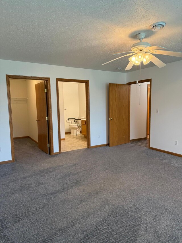 446 30th St N, Moorhead, MN 56560 - unfurnished bedroom featuring a closet, a textured ceiling, a spacious closet, carpet flooring, and baseboards