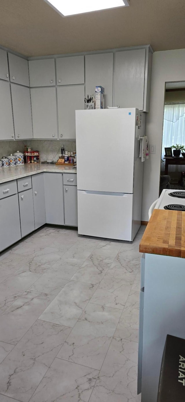 114 6th Ave, Albert Lea, MN 56007 - kitchen featuring freestanding refrigerator, light marble finish floors, and gray cabinetry