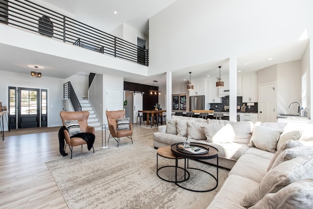 living area with a high ceiling, light wood finished floors, stairway, and recessed lighting