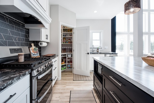 kitchen featuring double oven range, custom exhaust hood, black microwave, white cabinets, and recessed lighting