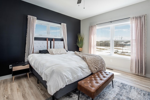 bedroom with light wood finished floors, baseboards, and ceiling fan