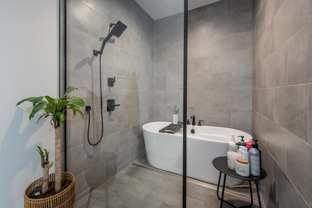 bathroom featuring a freestanding tub, tiled shower, and tile walls
