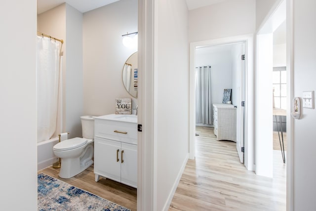 full bath featuring wood finished floors, vanity, toilet, shower / tub combo, and baseboards