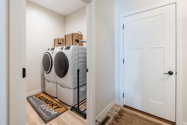 laundry area featuring washing machine and dryer, wood finished floors, and baseboards