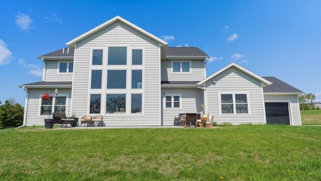 rear view of property featuring a yard, an attached garage, and a patio