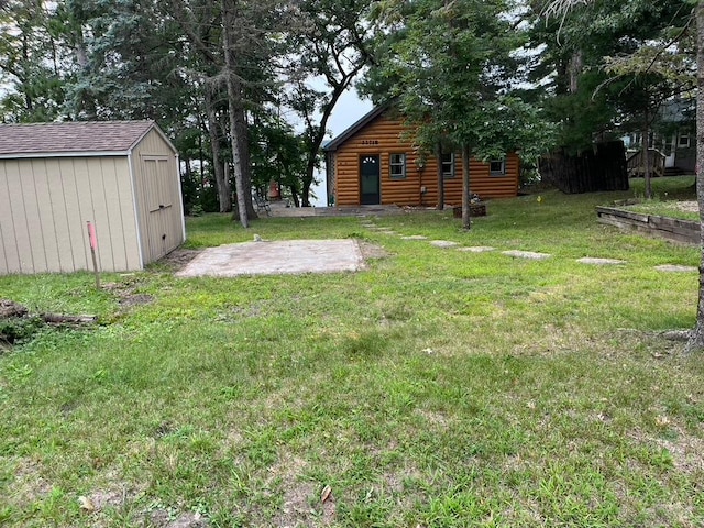 view of grassy yard with a storage shed, an outbuilding, and a patio area