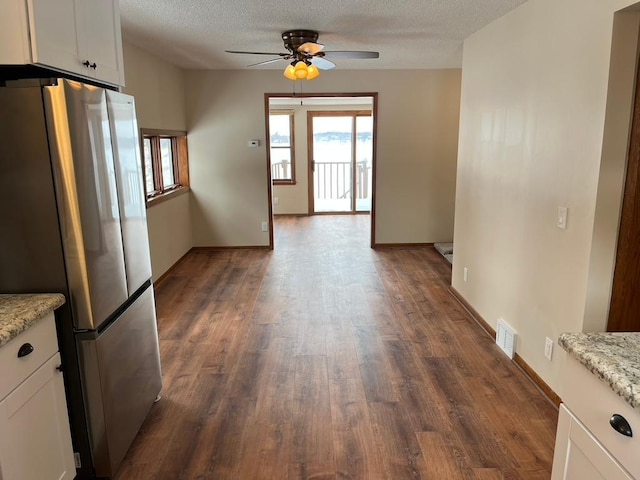 unfurnished dining area featuring a ceiling fan, dark wood-style flooring, a textured ceiling, and baseboards