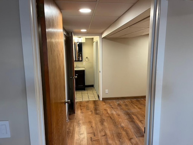 hall with wood finished floors, recessed lighting, and a sink