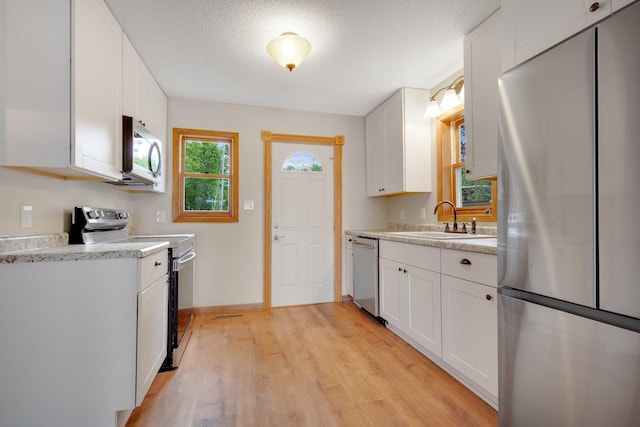 22718 Martin Lake Dr NE, Linwood Twp, MN 55092 - kitchen with appliances with stainless steel finishes, light countertops, light wood-style flooring, white cabinets, and a textured ceiling