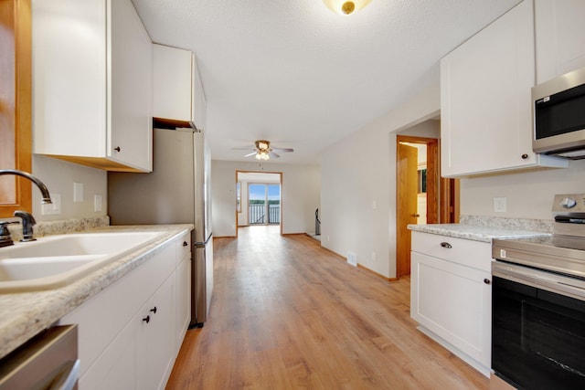 22718 Martin Lake Dr NE, Linwood Twp, MN 55092 - kitchen with stainless steel appliances, white cabinets, light wood-type flooring, and light countertops