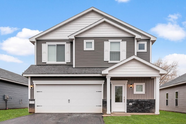 402 Redwood St N, Cambridge, MN 55008 - view of front facade with an attached garage, asphalt driveway, stone siding, and board and batten siding